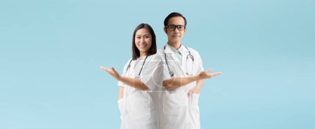 Foto de Servicios médicos. Asiático médico mujer y hombre, mano abierta palmera espacio de trabajo en blanco, aislado sobre fondo azul - Imagen libre de derechos