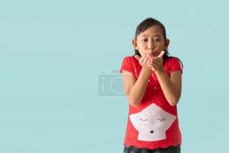 Foto de Retrato de atractiva alegre niña asiática feliz con traje de Navidad vestido, enviando besos de aire posando, aislado sobre fondo azul claro pastel - Imagen libre de derechos