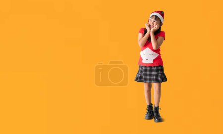 Foto de Jovencita alegre asiática vistiendo un suéter de Navidad con cuernos de reno, mirando pensando sorpresa de pie posando retrato de cuerpo completo, aislado sobre fondo amarillo - Imagen libre de derechos