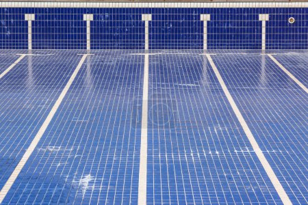 Photo for Swimming pool with blue tiles and swim lane tile markings empty of water for maintenance. - Royalty Free Image