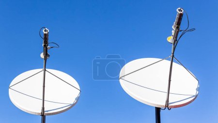 Satellite dishes digital communication two units close up against blue sky in remote countryside