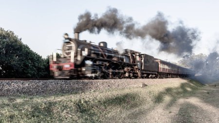 Photo for Steam Train locomotive with tourism coaches closeup motion speed blur on countryside rail line tracks travel route. - Royalty Free Image