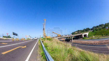 Photo for Construction Vertical Drilling Pylon Machine with Mobile Crane on road highway bridge expansion improvements roadside countryside perspective. - Royalty Free Image