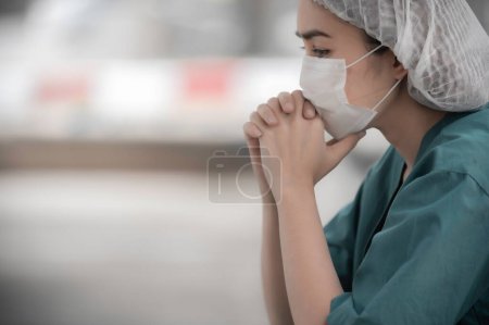 Photo for Tired depressed female asian scrub nurse wears face mask blue uniform sits on hospital floor,Young woman doctor stressed from hard work - Royalty Free Image