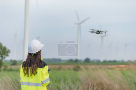 Photo for Engineers working and holding the report at wind turbine farm Power Generator Station on mountain,Thailand people,Technician man and woman discuss about wor - Royalty Free Image