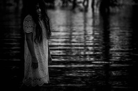 Téléchargez les photos : Portrait of asian woman make up ghost face at the swamp,Horror in water scene,Scary at river,Halloween poster,Thailand people - en image libre de droit