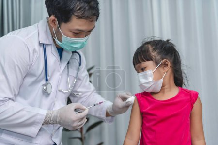 Téléchargez les photos : Asiatique médecin injection vaccin pour protéger le virus covid-19 à une fille porter un masque médical, Les gens sont les filles sont vaccinées contre la grippe chaque année. - en image libre de droit