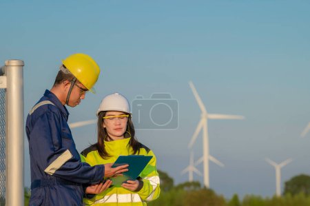 Téléchargez les photos : Deux ingénieurs travaillant et tenant le rapport au parc d'éoliennes Power Generator Station sur la montagne, Thaïlande personnes, Technicien homme et femme discuter du travail - en image libre de droit