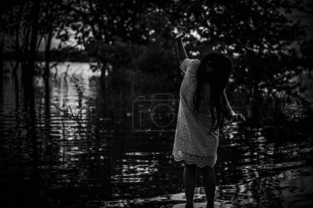Téléchargez les photos : Portrait of asian woman make up ghost face at the swamp,Horror in water scene,Scary at river,Halloween poster,Thailand people - en image libre de droit