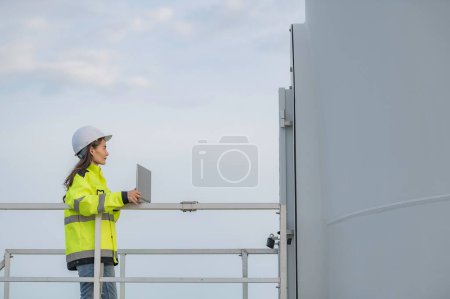 Photo for Women engineer working and holding the report at wind turbine farm Power Generator Station on mountain,Thailand people - Royalty Free Image