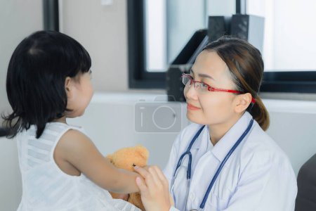 Téléchargez les photos : Médecin asiatique utilisant un stéthoscope pour vérifier sa respiration et le cœur d'une jolie fille, vérifier la santé des enfants, les gens de Thaïlande - en image libre de droit