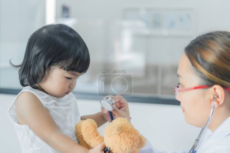 Téléchargez les photos : Médecin asiatique utilisant un stéthoscope pour vérifier sa respiration et le cœur d'une jolie fille, vérifier la santé des enfants, les gens de Thaïlande - en image libre de droit