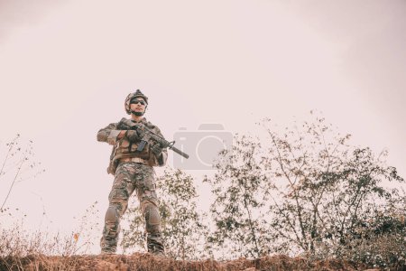 Téléchargez les photos : Soldat en attente sur la montagne avec une éruption et un soleil éclatant - en image libre de droit
