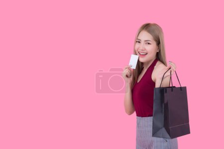 Foto de Hermosa mujer asiática con bolsa de compras y tarjeta de crédito en la mano sobre fondo rosa, Tailandia personas está utilizando una tarjeta de crédito y disfruta de compras - Imagen libre de derechos