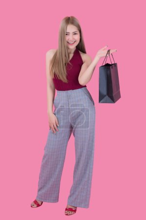 Téléchargez les photos : Belle femme asiatique avec sac à provisions et carte de crédit à la main sur fond rose, les gens de Thaïlande utilise une carte de crédit et aime faire du shopping - en image libre de droit