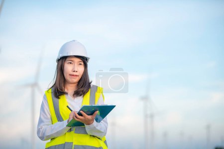 Téléchargez les photos : Femmes ingénieur travaillant et tenant le rapport au parc d'éoliennes Power Generator Station sur la montagne, Thaïlande personnes - en image libre de droit