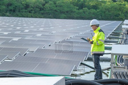 Foto de Ingeniero asiático trabajando en planta de energía solar flotante, energía renovable, técnico e inversor paneles solares comprobando los paneles en la instalación de energía solar - Imagen libre de derechos