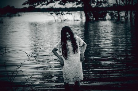 Foto de Portrait of asian woman make up ghost face at the swamp,Horror in water scene,Scary at river,Halloween poster,Thailand people - Imagen libre de derechos
