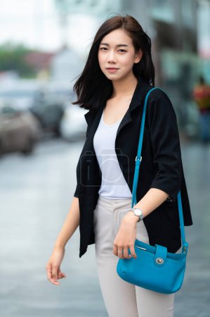 Téléchargez les photos : Belle femme asiatique marchant pour aller au travail, Jeune femme d'affaires réussie dans une grande ville - en image libre de droit
