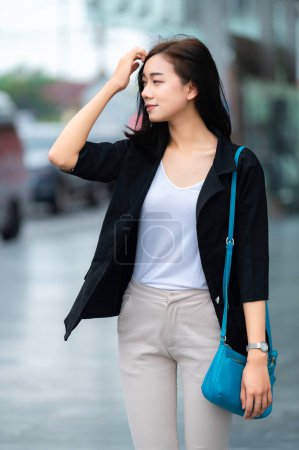 Téléchargez les photos : Belle femme asiatique marchant pour aller au travail, Jeune femme d'affaires réussie dans une grande ville - en image libre de droit