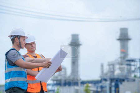 Foto de Dos ingenieros que trabajan en la planta de energía, trabajan juntos felizmente, se ayudan mutuamente a analizar el problema, consultan sobre las directrices de desarrollo - Imagen libre de derechos