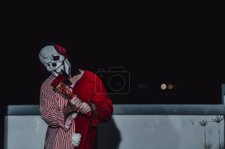 Photo for Asian handsome man wear clown mask with weapon at the night scene,Halloween festival concept,Horror scary photo of a killer in orange cloth,Evil clown charactor - Royalty Free Image