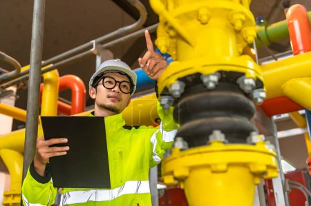 Téléchargez les photos : Ingénieur asiatique portant des lunettes travaillant dans la chaufferie, vérification de la maintenance des données techniques des équipements du système de chauffage, Thaïlande personnes - en image libre de droit