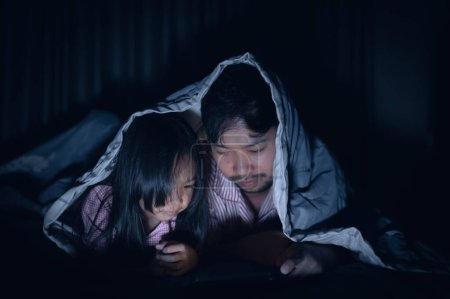 Photo for Dad and daughter sleep on the bed in bedroom,Watch cartoon with phone,Father day concept,Single dad,listen tale before sleep - Royalty Free Image