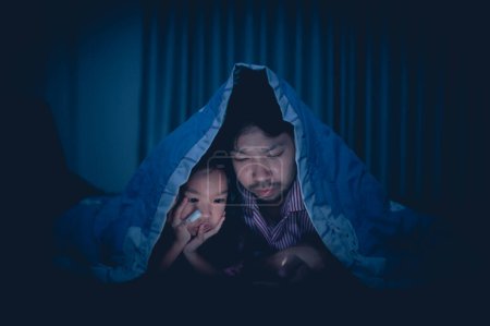 Foto de Dad and daughter sleep on the bed in bedroom,Watch cartoon with phone,Father day concept,Single dad,listen tale before sleep - Imagen libre de derechos