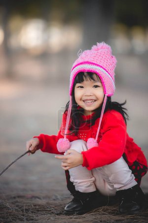 Téléchargez les photos : Portrait de mignonne petite fille asiatique porter des vêtements d'hiver à la forêt du parc, les gens de Thaïlande posent pour prendre une photo, Happy time - en image libre de droit