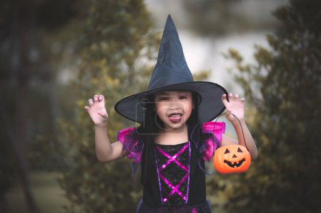 Foto de Asian cute female kid wear witch costume with pumkin,Halloween festival concept - Imagen libre de derechos
