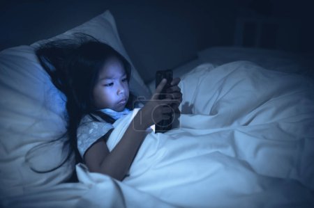 Téléchargez les photos : Femme asiatique jouant au jeu sur smartphone dans le lit la nuit, Thaïlande personnes, Addict médias sociaux - en image libre de droit