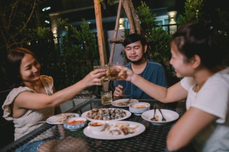 Photo for Group of asian people dinning party in the garden of home on holiday,Summer evening garden party celebration with Friends - Royalty Free Image
