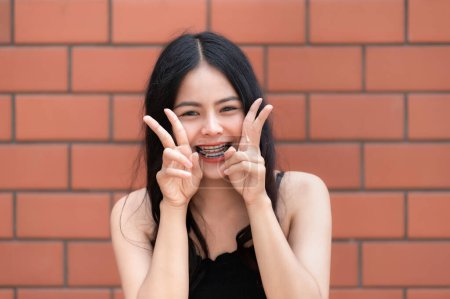 Téléchargez les photos : Portrait de fille hipster sur fond de mur de briques, Belle pose de femme asiatique pour prendre une photo, style Kawaii - en image libre de droit