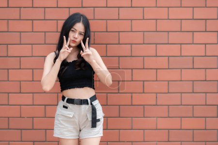 Téléchargez les photos : Portrait de fille hipster sur fond de mur de briques, Belle pose de femme asiatique pour prendre une photo, style Kawaii - en image libre de droit