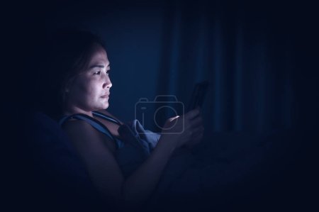 Téléchargez les photos : Femme asiatique jouer smartphone dans le lit la nuit, Thaïlande personnes - en image libre de droit