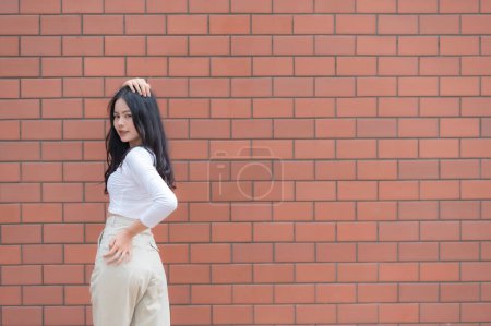 Foto de Retrato de chica hipster en el fondo de la pared de ladrillo, Hermosa pose de mujer asiática para tomar una foto, estilo Kawaii - Imagen libre de derechos