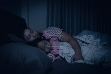 Foto de Dad and daughter sleep on the bed in bedroom,Watch cartoon with phone,Father day concept,Single dad,listen tale before sleep - Imagen libre de derechos