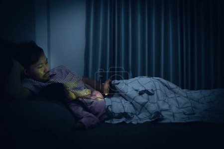 Téléchargez les photos : Dad and daughter sleep on the bed in bedroom,Watch cartoon with phone,Father day concept,Single dad,listen tale before sleep - en image libre de droit