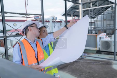 Téléchargez les photos : Two young engineers working together,Discuss the construction of a warehouse,See the construction drawings for the storage facility. - en image libre de droit
