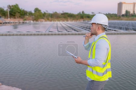 Téléchargez les photos : Ingénieur asiatique travaillant chez Floating Solar Farm, Energie renouvelable, Technicien et investisseur panneaux solaires vérifiant les panneaux à l'installation d'énergie solaire - en image libre de droit