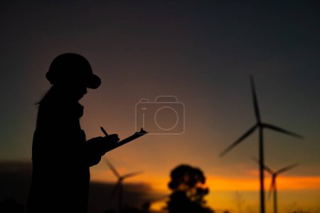 Photo for Asian Man engineers working and holding the report at wind turbine farm Power Generator Station on mountain,Thailand people,Technician man at site of work - Royalty Free Image