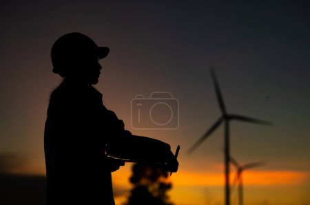 Photo for Asian Man engineers working and holding the report at wind turbine farm Power Generator Station on mountain,Thailand people,Technician man at site of work - Royalty Free Image
