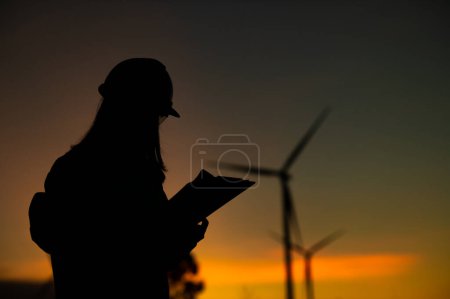 Téléchargez les photos : Asian Man ingénieurs travaillant et tenant le rapport au parc d'éoliennes Power Generator Station sur la montagne, Thaïlande personnes, Technicien homme sur le site de travail - en image libre de droit
