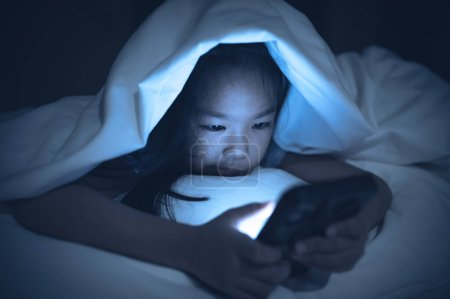 Téléchargez les photos : Femme asiatique jouant au jeu sur smartphone dans le lit la nuit, Thaïlande personnes, Addict médias sociaux - en image libre de droit