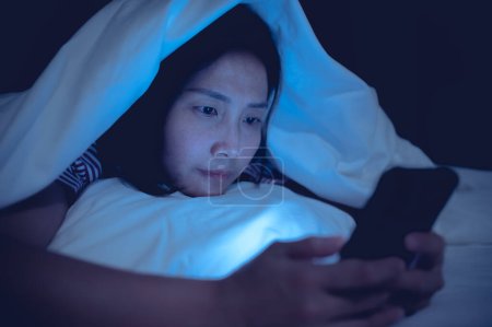 Photo for Asian woman playing game on smartphone in the bed at night,Thailand people,Addict social media - Royalty Free Image