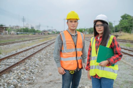 Foto de Dos ingenieros que trabajan en la estación de tren, trabajan juntos felizmente, se ayudan mutuamente a analizar el problema, consultan sobre las directrices de desarrollo - Imagen libre de derechos