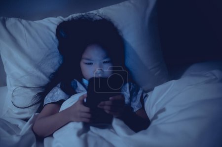 Photo for Asian kid playing game on smartphone in the bed at night,The girl Addict social media - Royalty Free Image