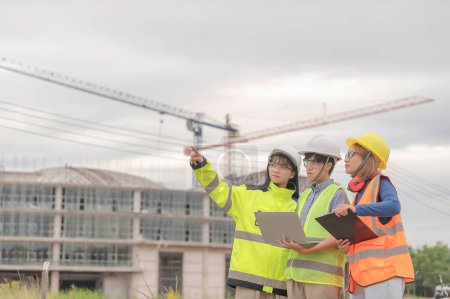 Photo for Young and senior Engineers discuss about work of large building underconstruction,Three people working on site of under construction - Royalty Free Image