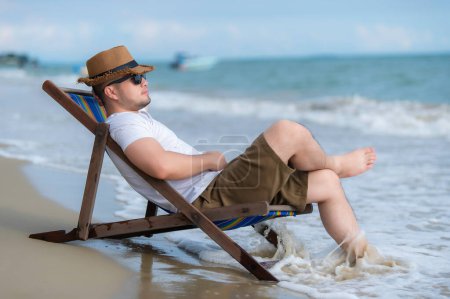 Foto de Asiático hombre sentado silla playa dentro del mar, relajarse tiempo en verano - Imagen libre de derechos